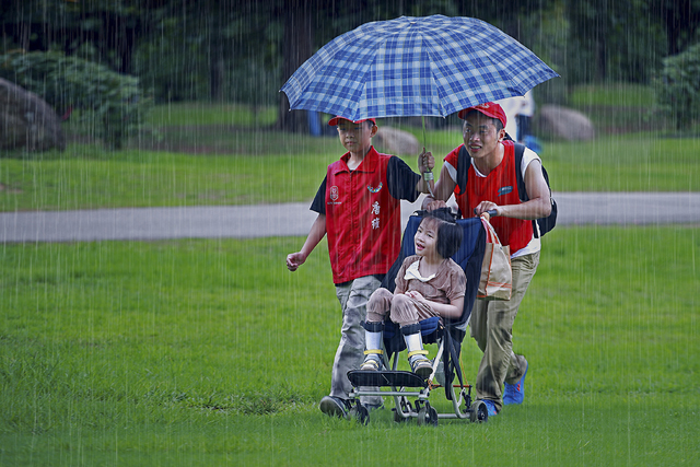 吳斌 《義工冒雨送殘障孩童》 中國廣東.jpg